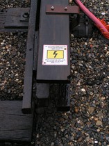 Dans les gares, le rail conducteur est protégé par des planches qui portent des messages d’avertissement.